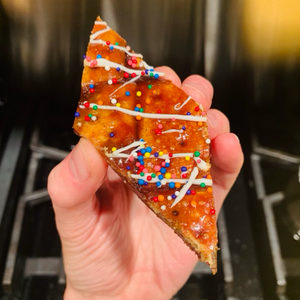A hand holding a piece of gingerbread toffee